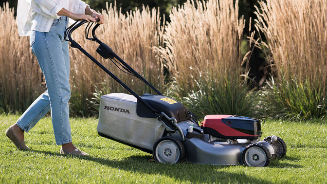 side view of woman using with honda izy-on lawnmower in the garden
