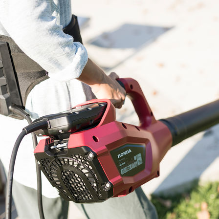 reverse angle view of man with honda cordless leaf blower in hand