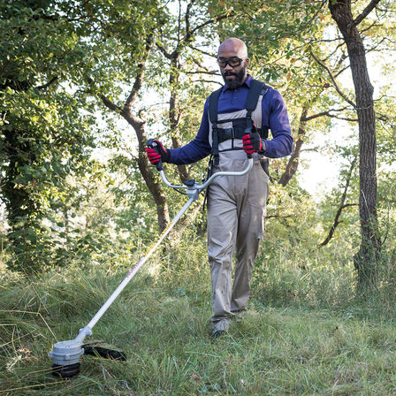 photo of man cutting overgrown grass with honda cordless brushcutter/strimmer