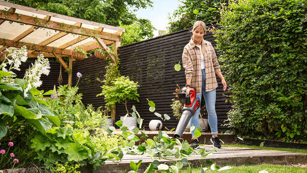 Woman using a Cordless Leafblower in garden