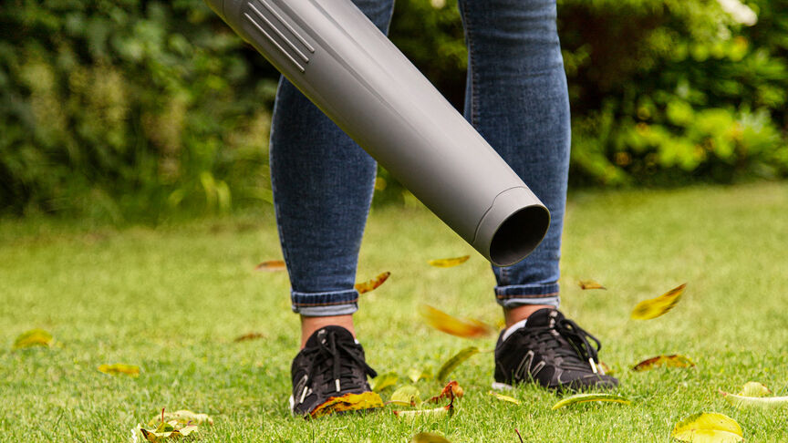 Lady in sneakers using Cordless Leafblower