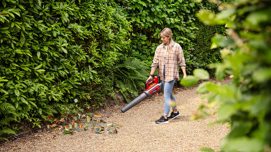 Lady in sneakers using Cordless Leafblower