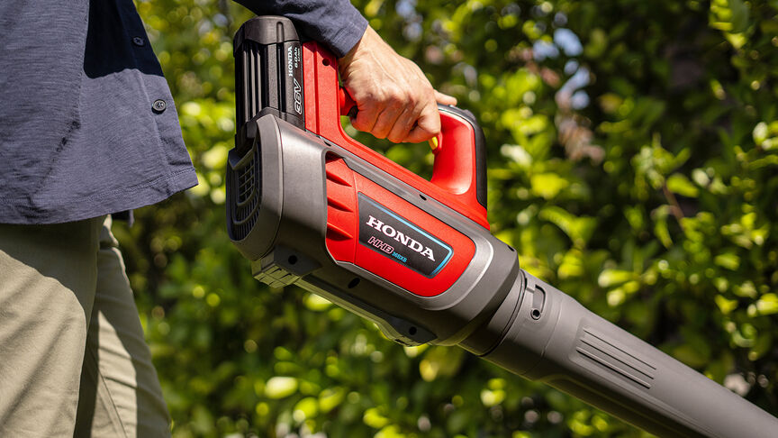 Lady in sneakers using Cordless Leafblower