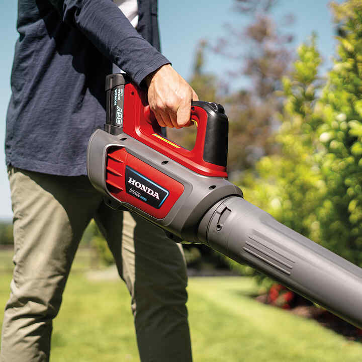 Man using a codrless leafblower in a garden.