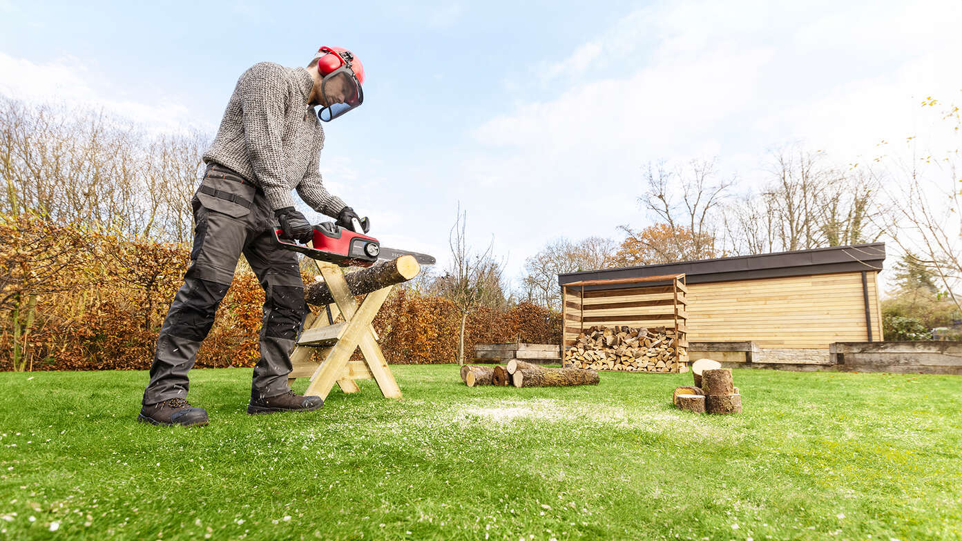 Man using a Cordless Chainsaw in a garden location.