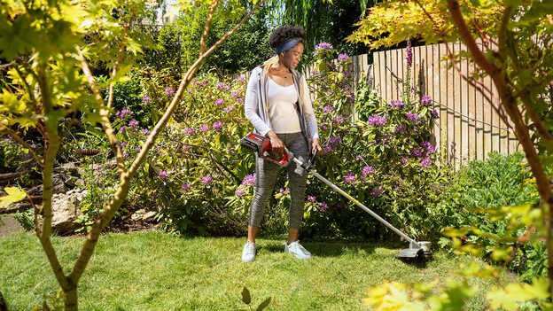 Woman in garden location using the Honda Cordless lawntrimmer.