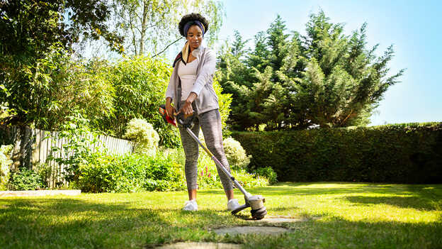 Woman using Honda Cordless lawntrimmer on grass in a garden location.