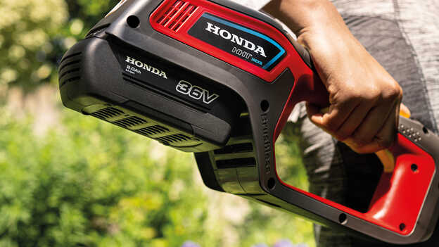 Close up of model holding Honda cordless lawntrimmer