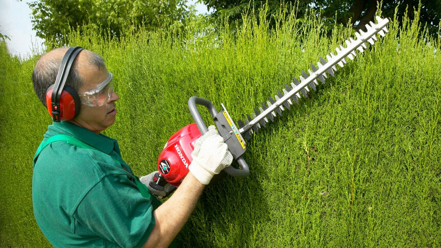 Man using hedgetrimmer with noise cancellation headphones