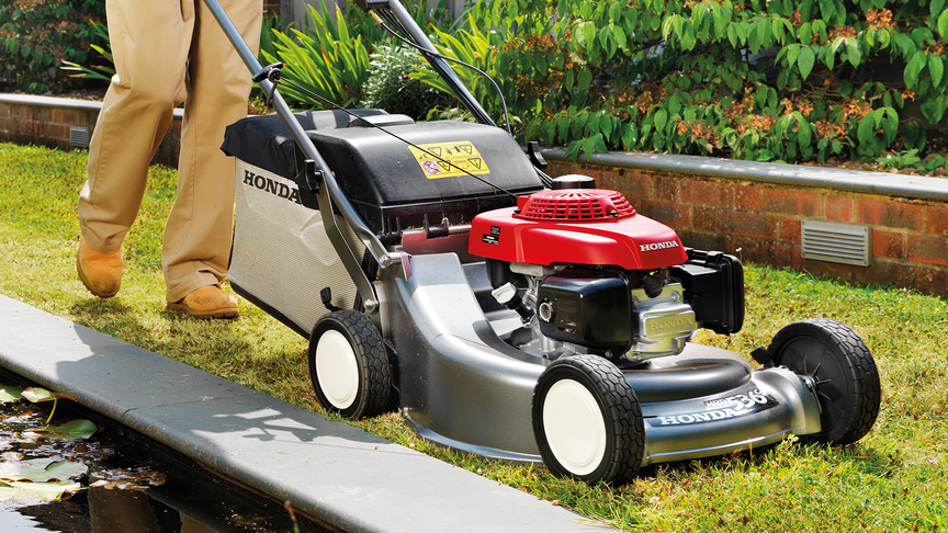 Man in garden location mowing grass with a Honda HRD lawnmower.