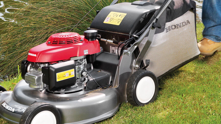 Man in garden location mowing grass with a Honda HRD lawnmower.