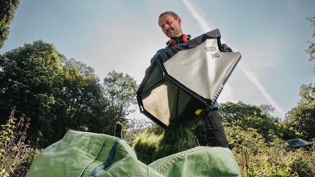 Man emptying large grass bag.