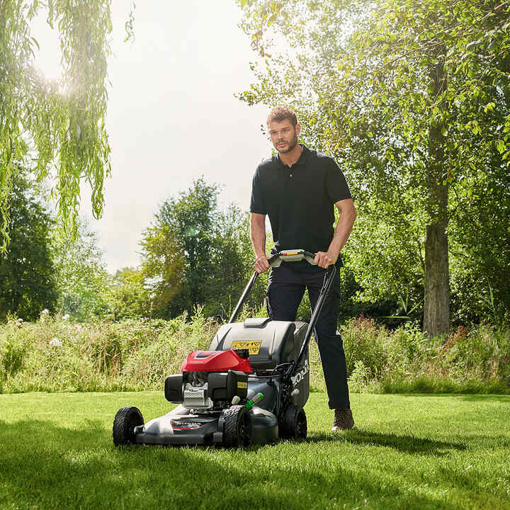 Man using HRN lawnmower in garden location.