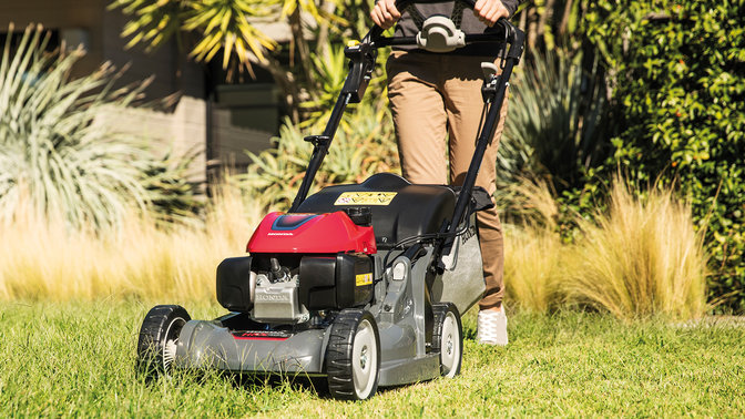 front side view of person mowing overgrown lawn with honda hrx petrol lawnmower