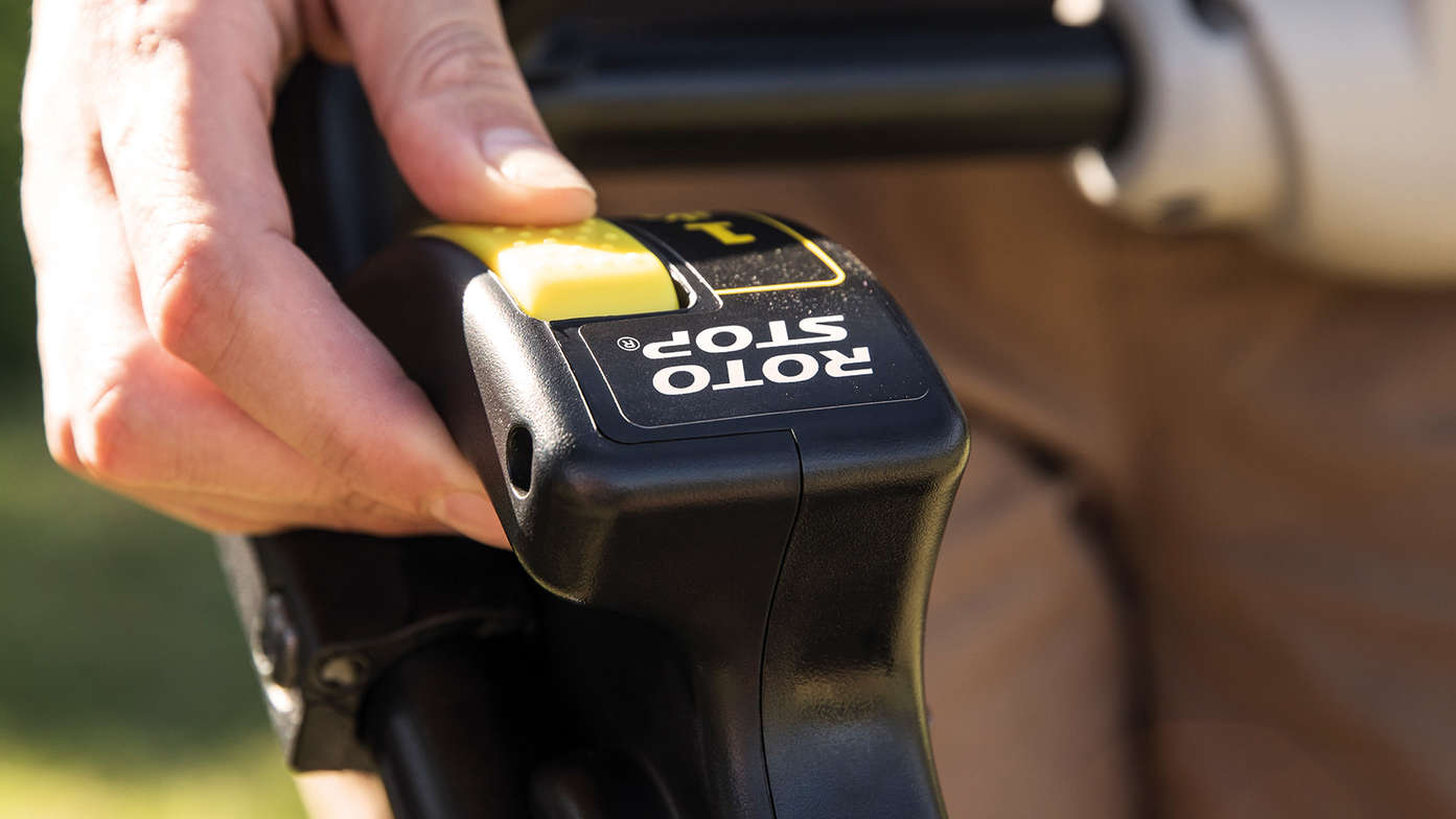 close up view of someone operating roto-stop system control of honda hrx petrol lawnmower