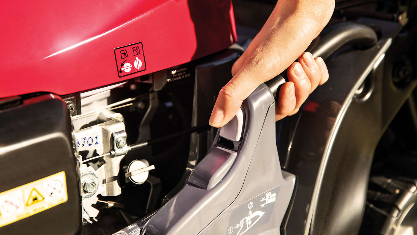 close up of person using the honda hrx petrol lawnmower with cutting height adjustment control