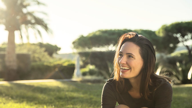 photo of smiling woman in a garden on a sunny day with palm trees