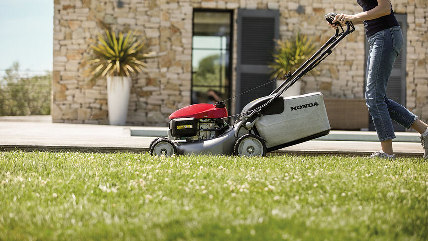 Honda IZY lawnmower side view with woman in garden