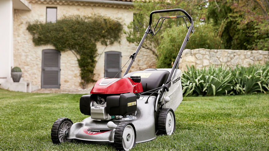 Honda IZY lawnmower side view with woman in garden