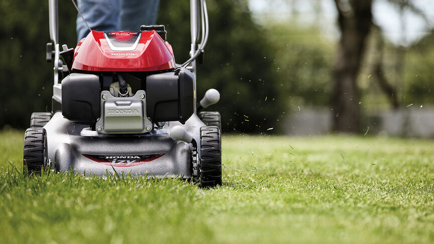 Honda IZY lawnmower side view with woman in garden