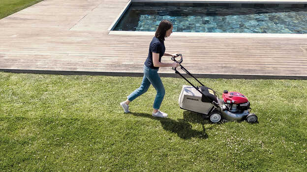 Honda IZY lawnmower side view with large grass bag capacity in garden location