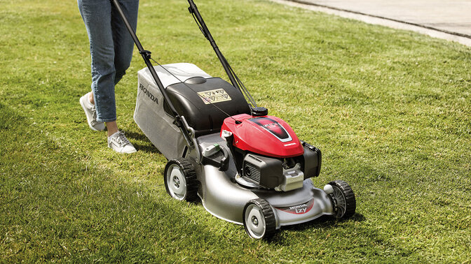 Lady with Honda IZY lawnmower cutting grass in garden location