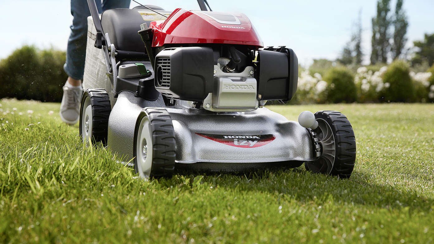 Honda IZY lawnmower size view with woman in garden location
