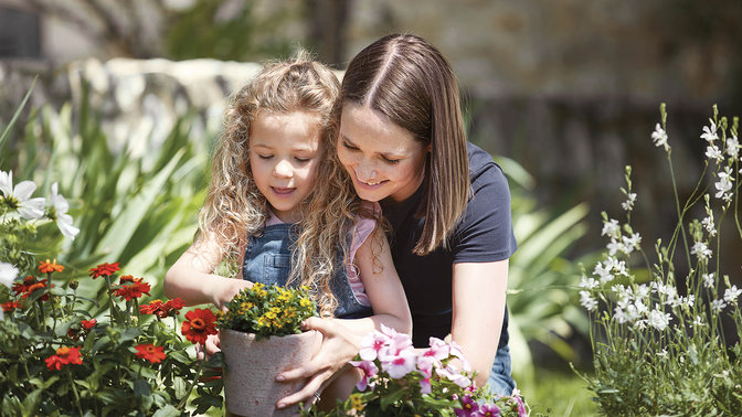 mom and daughter admiring flowers in the garden