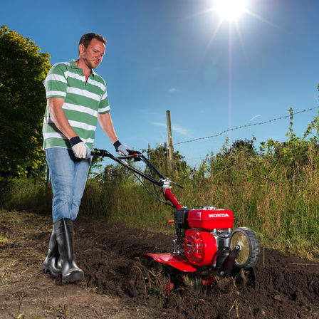 Compact tiller, being used by model, garden location.
