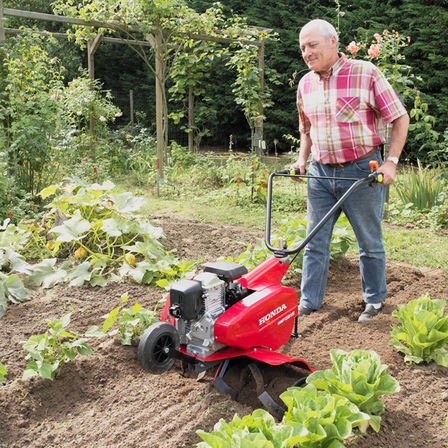 Compact tiller, being used by model, garden location.
