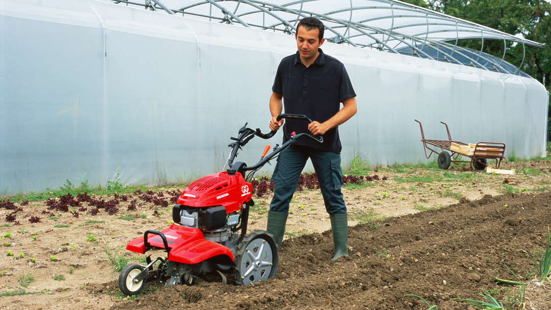 Rotary tiller, being used by model, garden location.