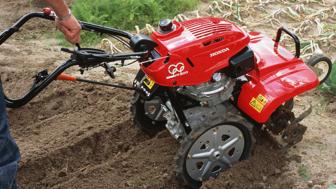 Close up of Rotary tiller, focusing on adjustable handles, garden location.