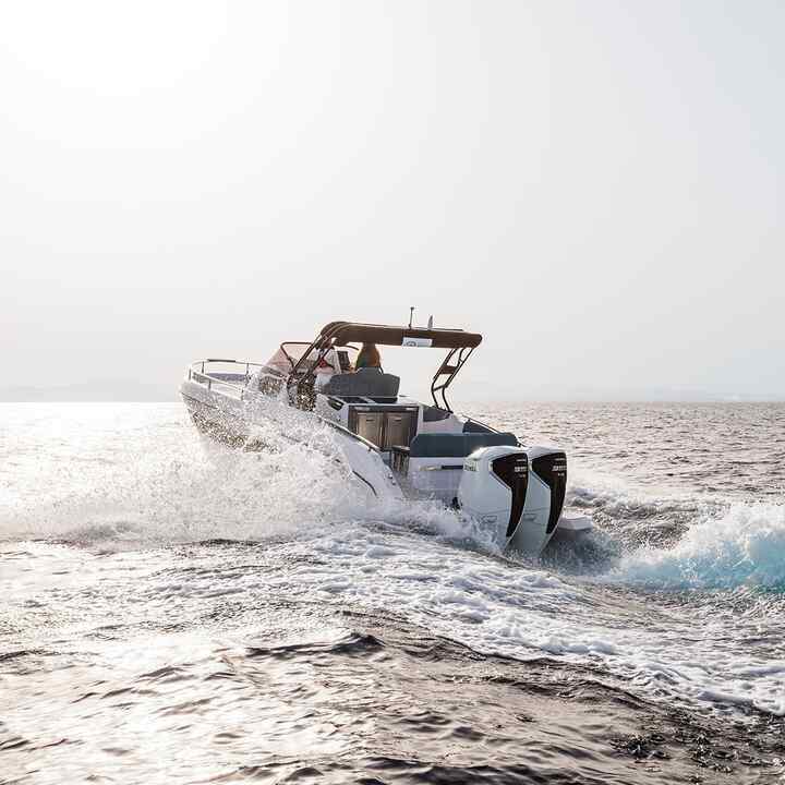 Two models driving boat in the sea with Honda BF350 v8 engine.