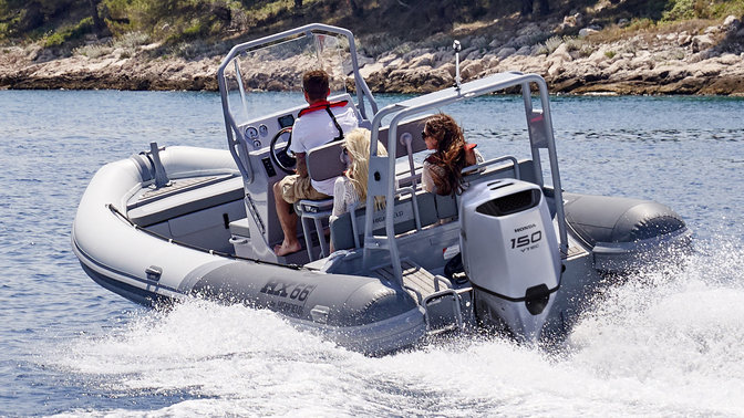 side angled view of people steering a boat on the water powered by a honda outboard engine