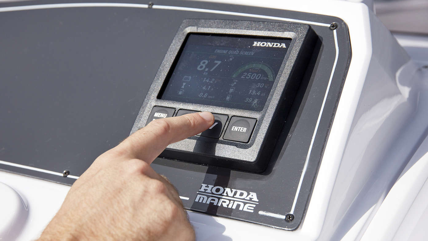 close up on someone using the multifunction colour display of a honda marine engine