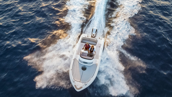 aerial view of a couple steering a boat with the wake of the boat behind them