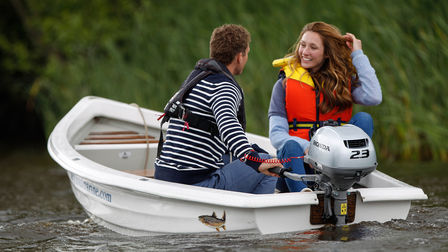 rear view of couple steering a boat fitted with a the honda 2-3 horsepower outboard engine