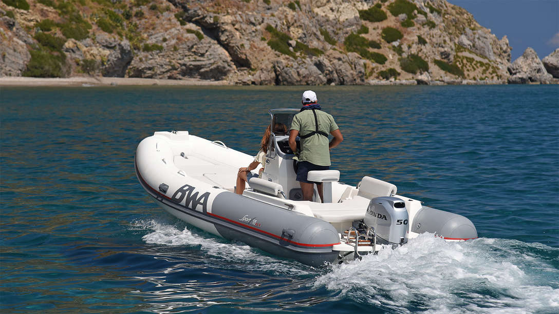 rear angled of man steering a boat fitted with a 50 horsepower honda marine engine