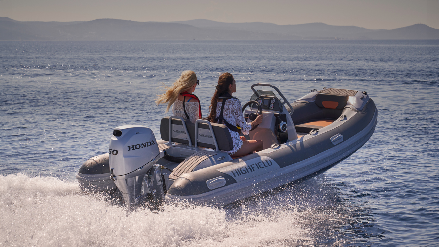 Two models on a Highfield boat with Honda BF50 engine in sea location.