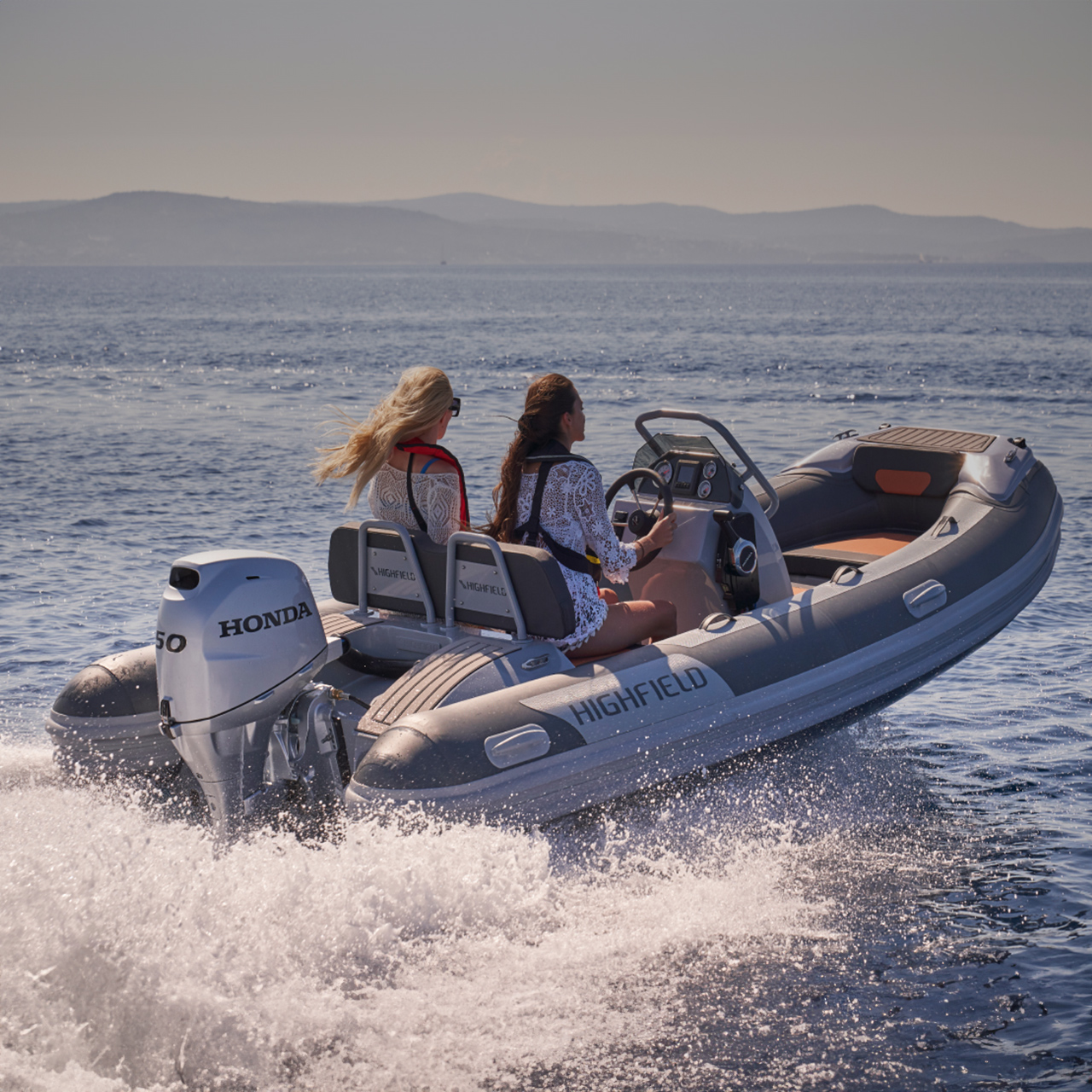 Two models on a Highfield boat with Honda BF50 engine in sea location.