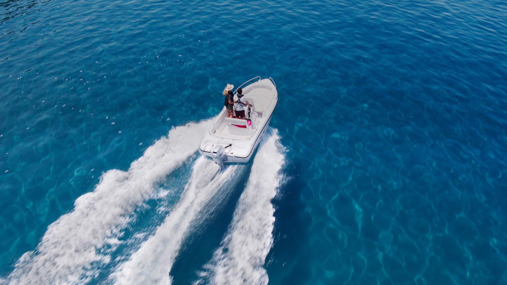 Couple on a boat in the ocean with a Honda BF engine.