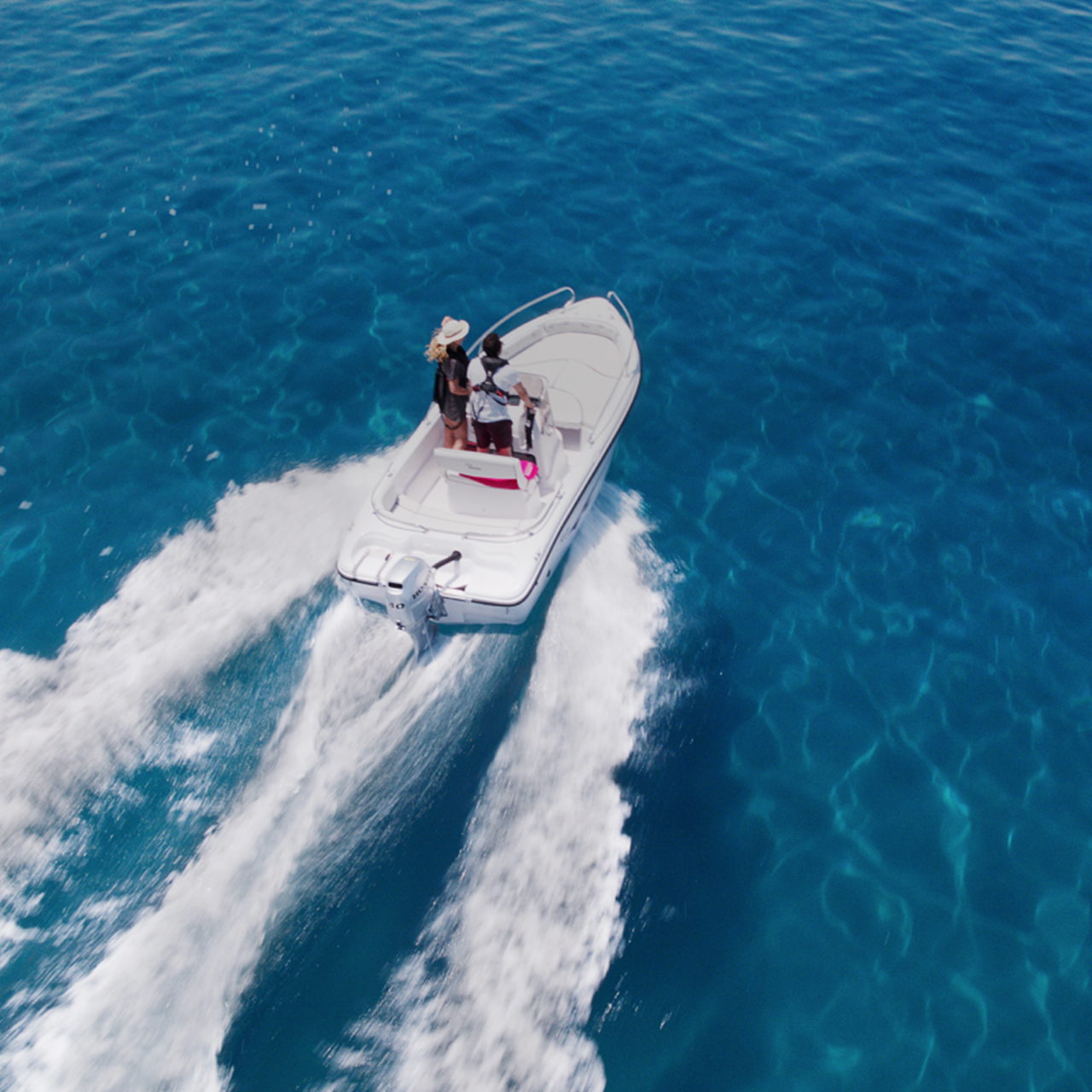 Couple on a boat in the ocean with a Honda BF engine.