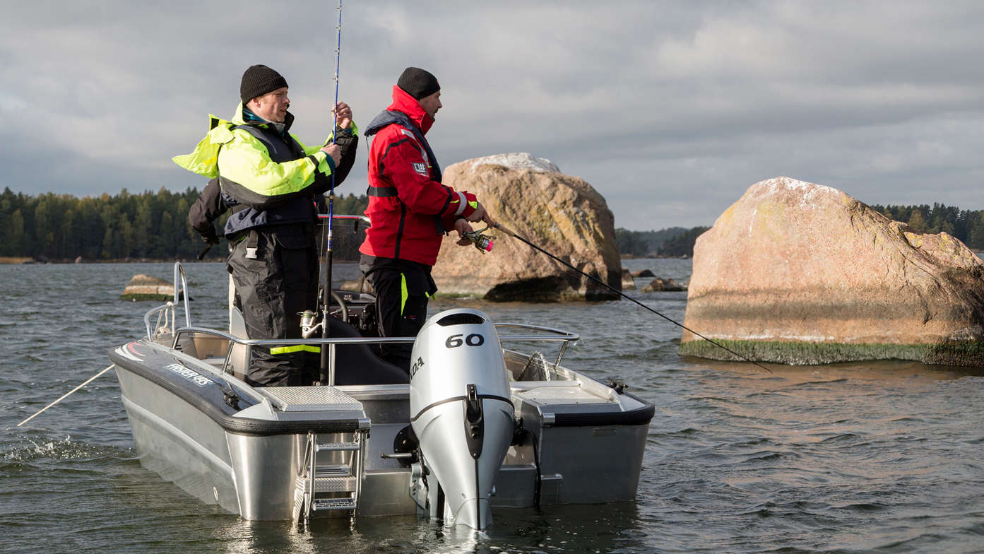 rear angled view of two men fishing on a boat powered by a 60 horsepower honda outboard engine