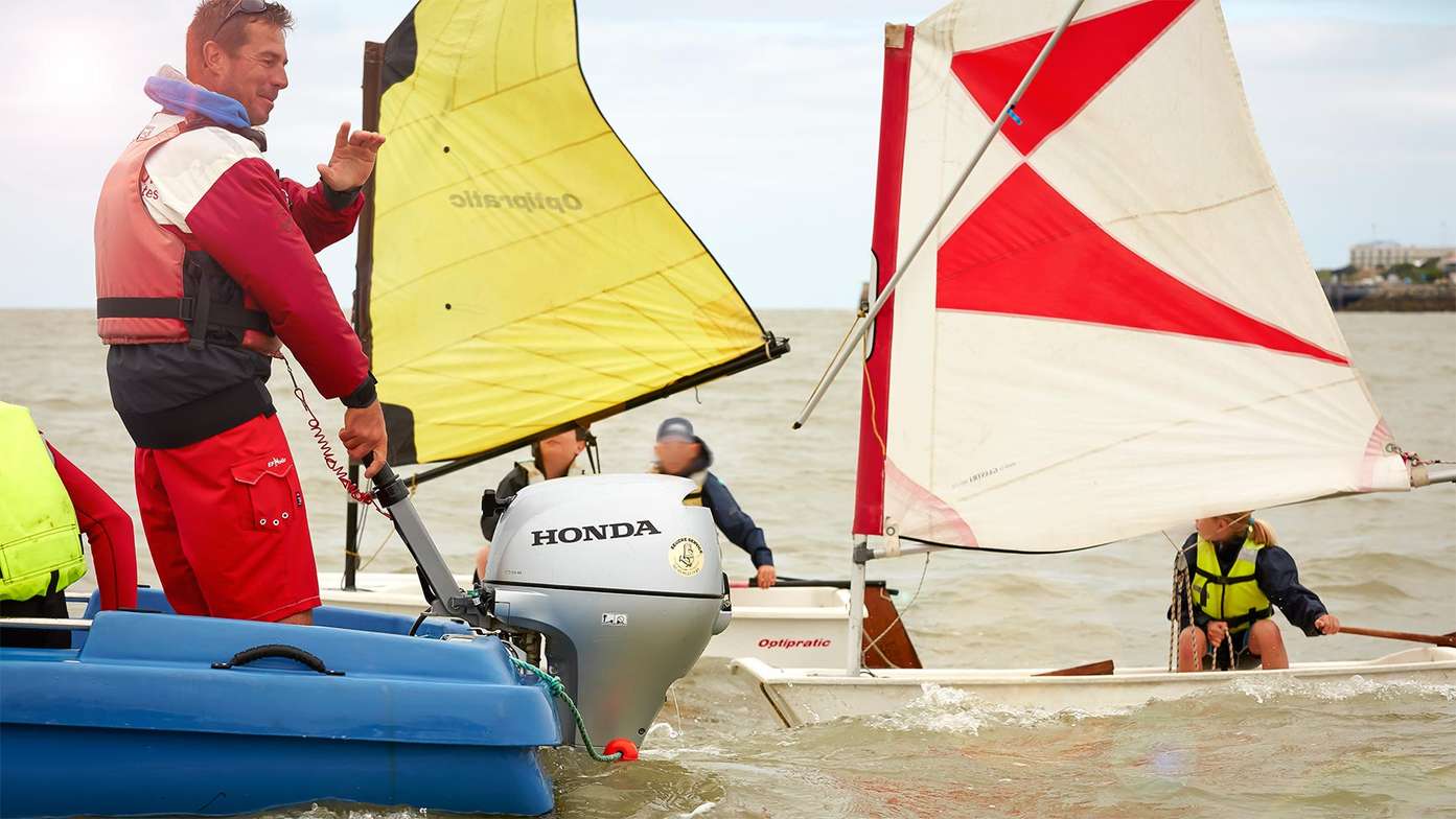 side view of man on blue boat fitting with honda marine engine at a boat racing event