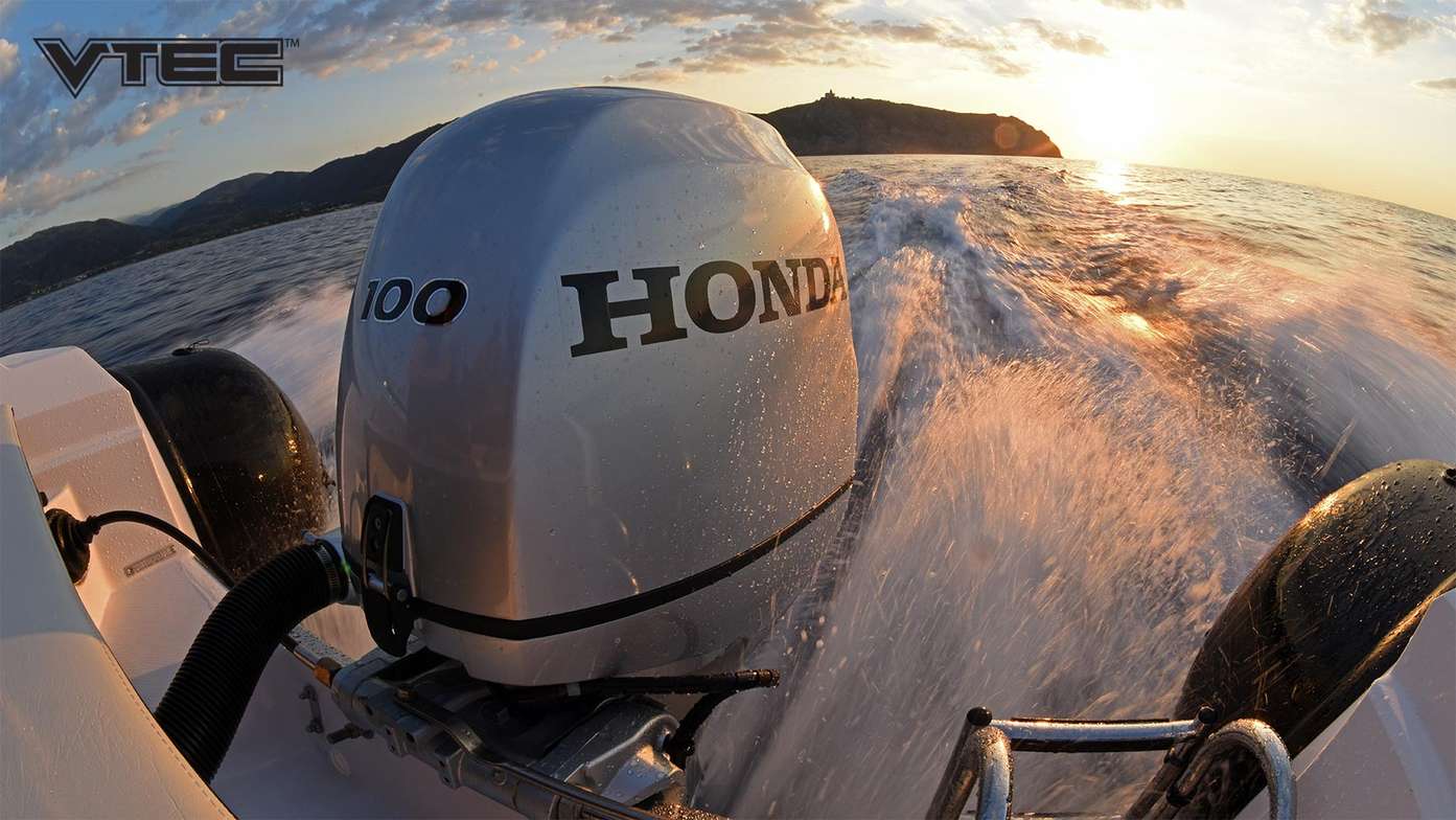 close up of a 100 horsepower honda outboard engine attached to the back of a boat on the water