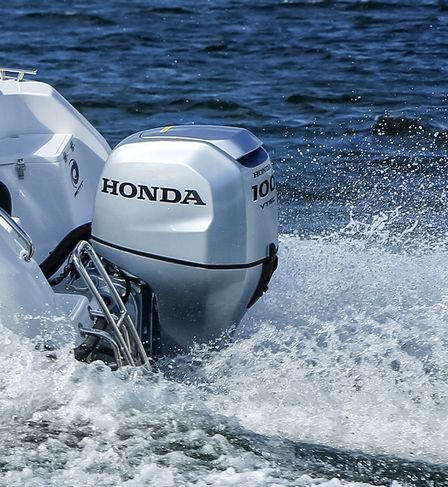 close up of a honda bf 100 attached to the back of a boat on the water