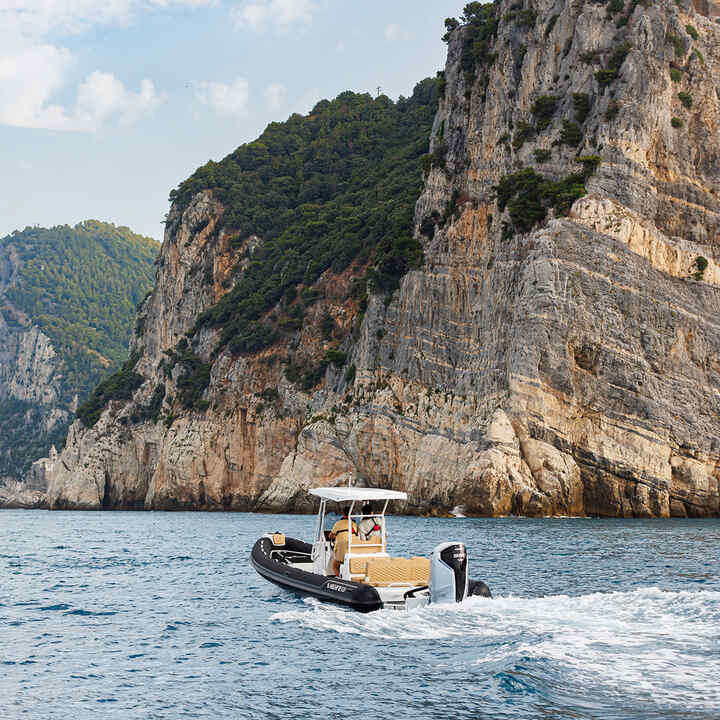 Speed boat at sea by a cliff