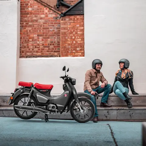 Honda Supercub 125 static on location with rider and pillion