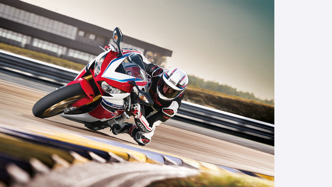 Front, 3-quarter view of Fireblade with rider, cornering in race track location. Right facing.