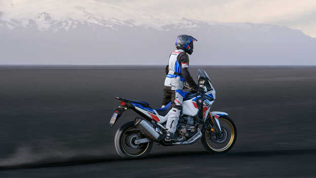 Rear three quarter Honda Africa twin being ridden across the dunes.